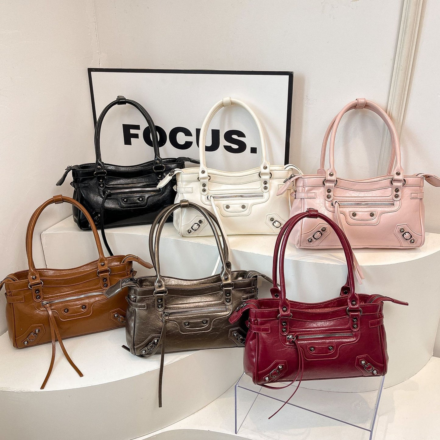 Collection of handbags in various colors on a white surface with 'FOCUS.' text in the background.